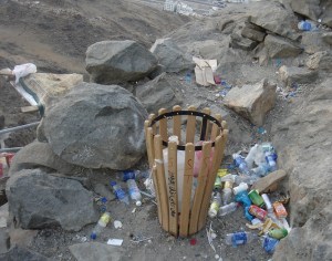 A garbage can lies half empty, while garbage is thrown on the ground next to it.