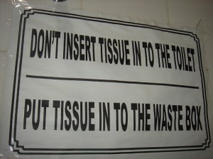 The sign says: "Don't insert tissue into the toilet. Put tissue into the waste box."